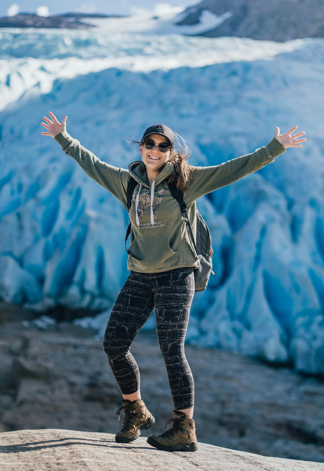 Person with arms outstretched in front of a glacier